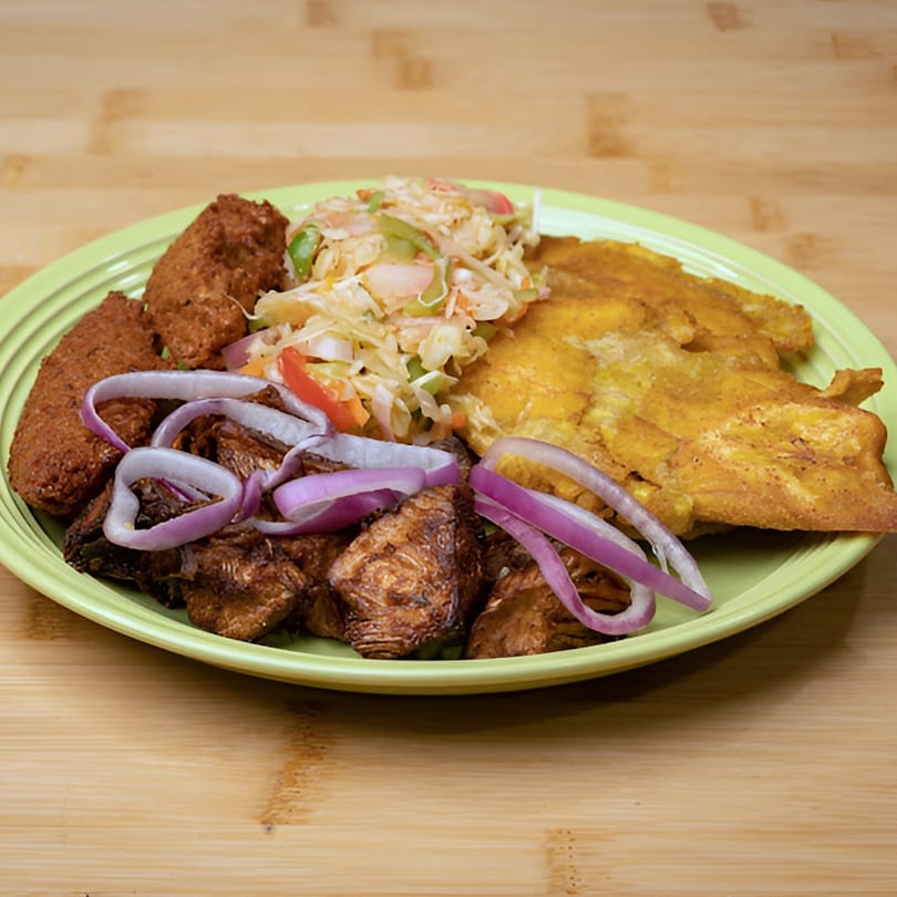A vegan meal with plantains, fried plant-based protein, and a side salad with red onions.